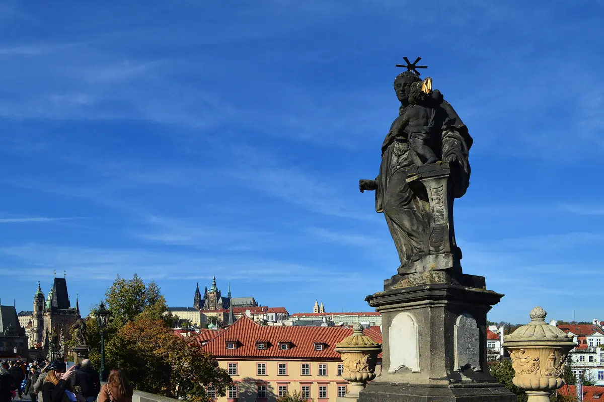 A statue on the bridge with the castle behind